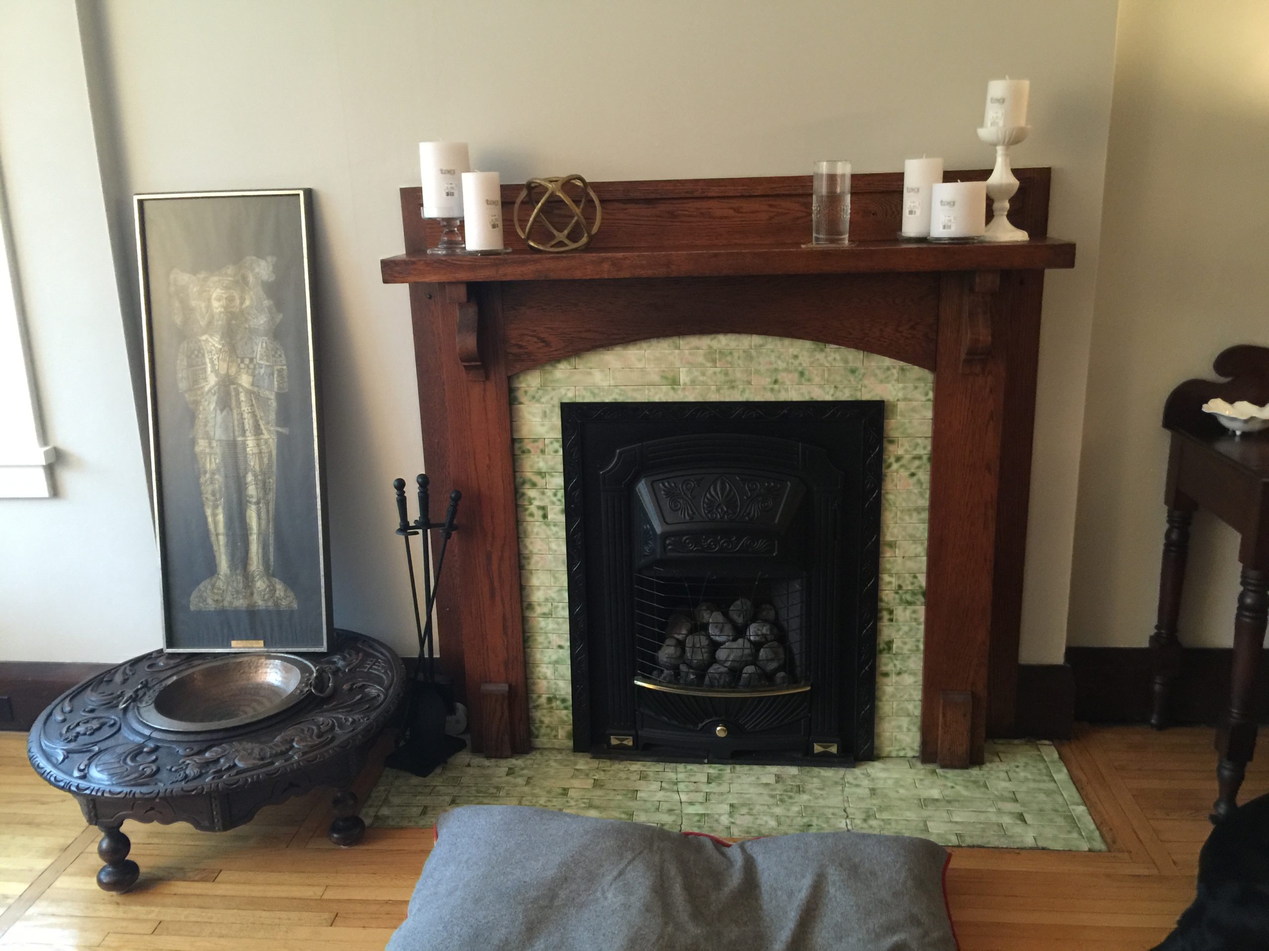 before photo of living room fireplace that has a wood mantel and green tile surround
