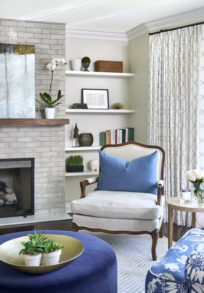 bright corner of living room with an antique chair reupholstered in a natural linen and blue velvet decorative pillow on it