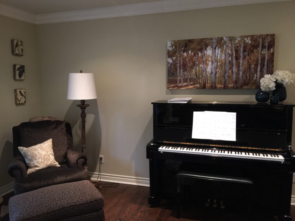 before photo of Oakville living room with beige walls, dark brown chair, and black piano against the wall
