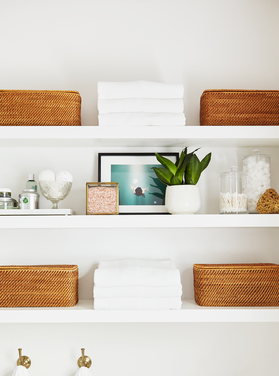 white floating shelves beautifully styled with bathroom accessories, baskets, and neatly folded white towels