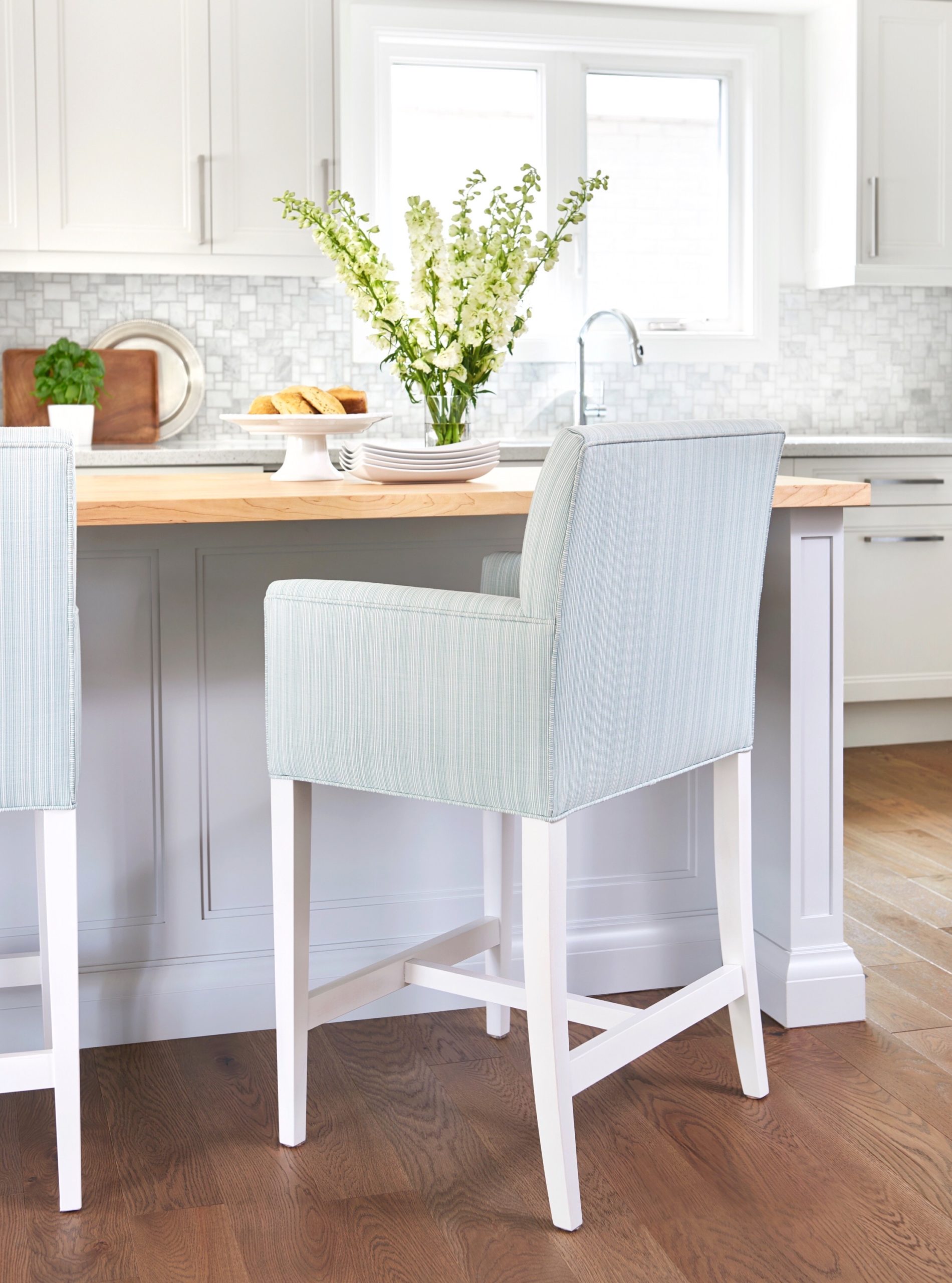 kitchen island with an upholstered stool in front that has white legs and a light blue fabric