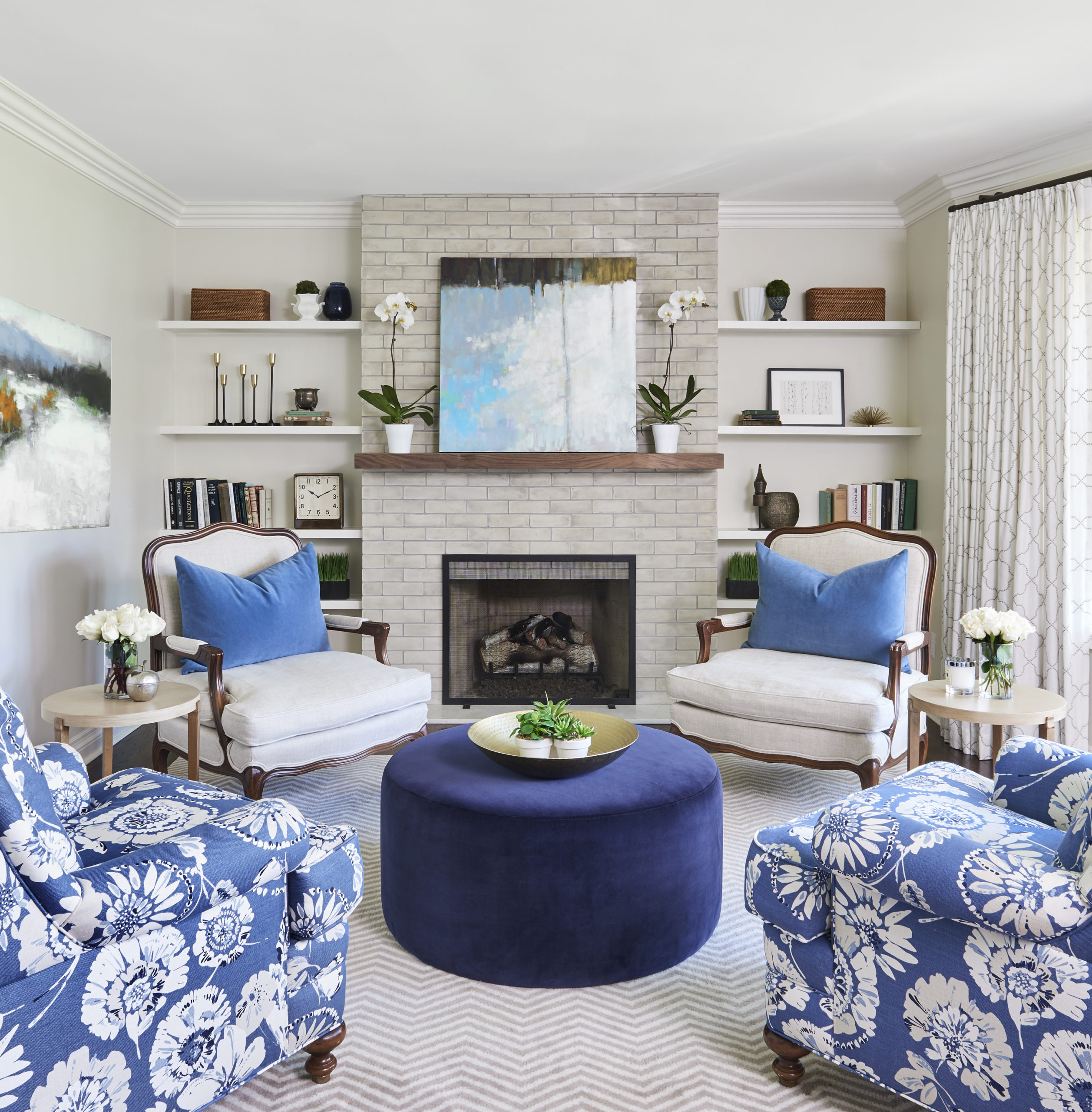 beautiful oakville living room with brick surround fireplace, antique chairs, and navy velvet ottoman