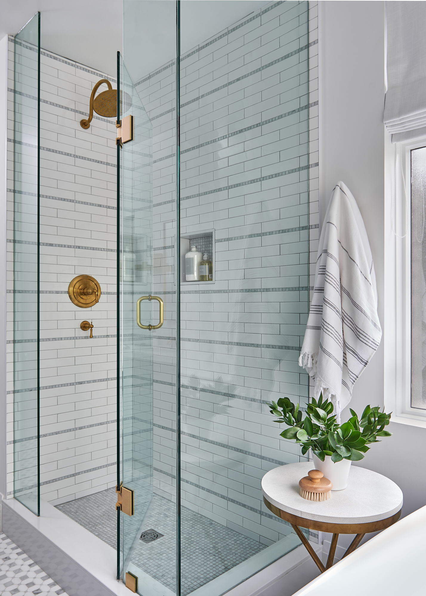 corner of Toronto bathroom with custom shower with white and marble tile and gold fixtures