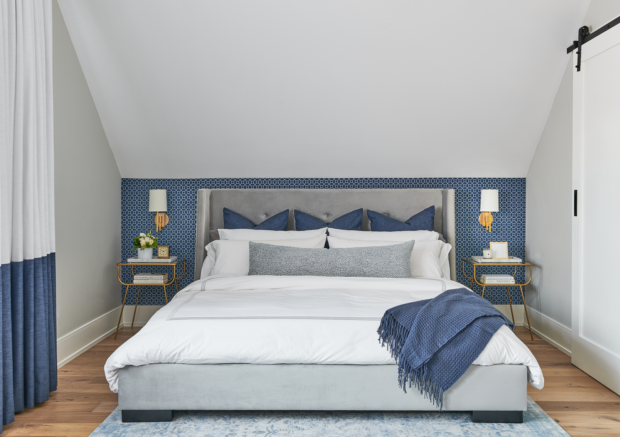 beautiful bedroom with bed styled with blue and white bedding, toss pillows, and throw blanket