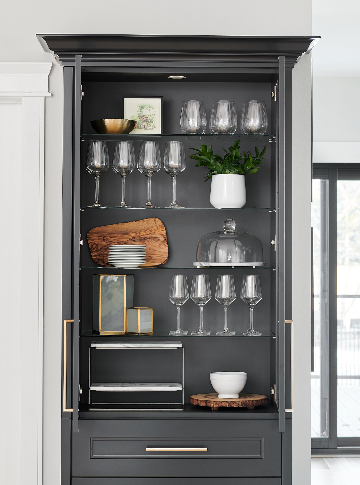 custom cabinet styled with wine glasses, serving trays, and greenery