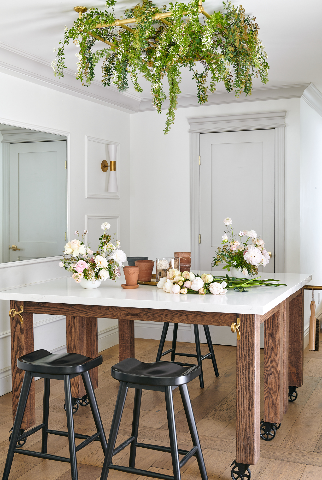 floral studio table on wheels with black wooden stools around and flower arrangements on top