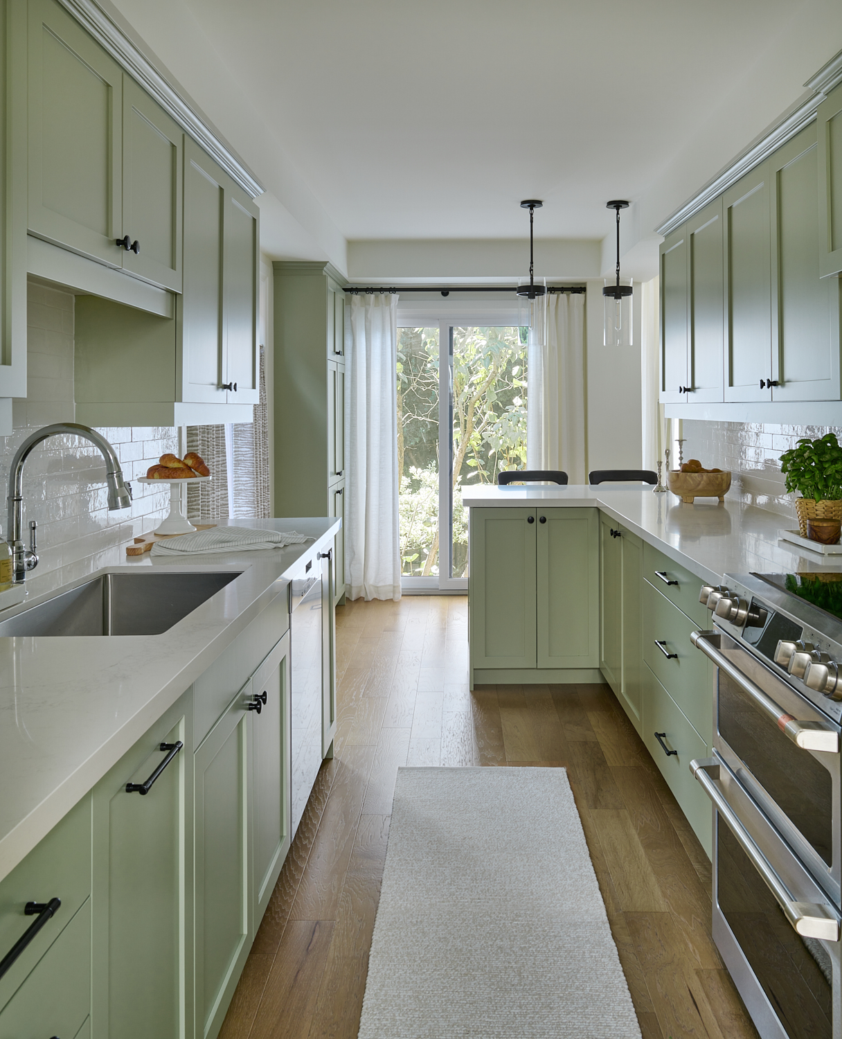 kitchen with light green cabinets, oak wood floors, white countertops and tiled backsplash