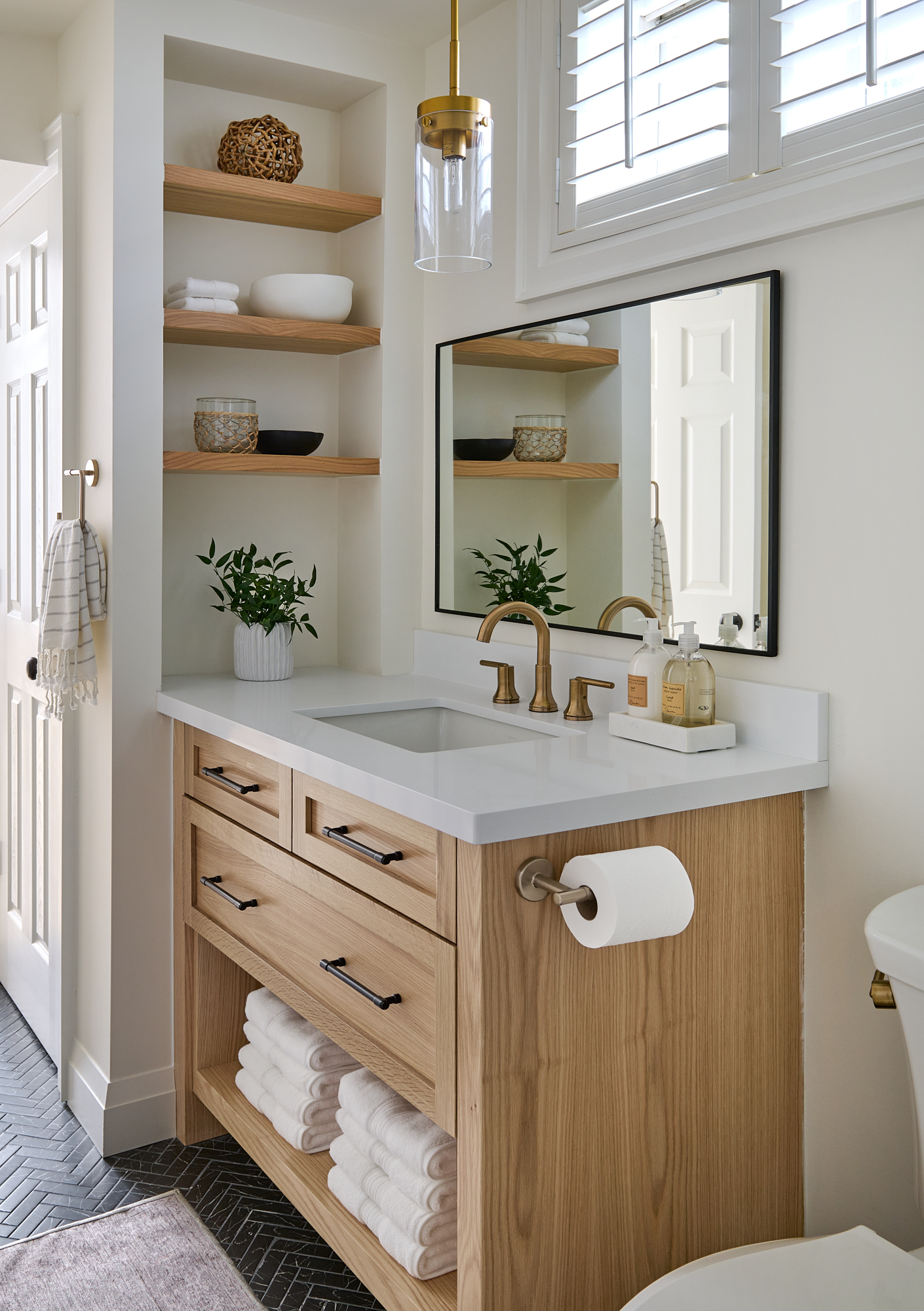 bathroom interior designed with oak wood vanity, gold plumbing fixtures and open shelving next to the vanity