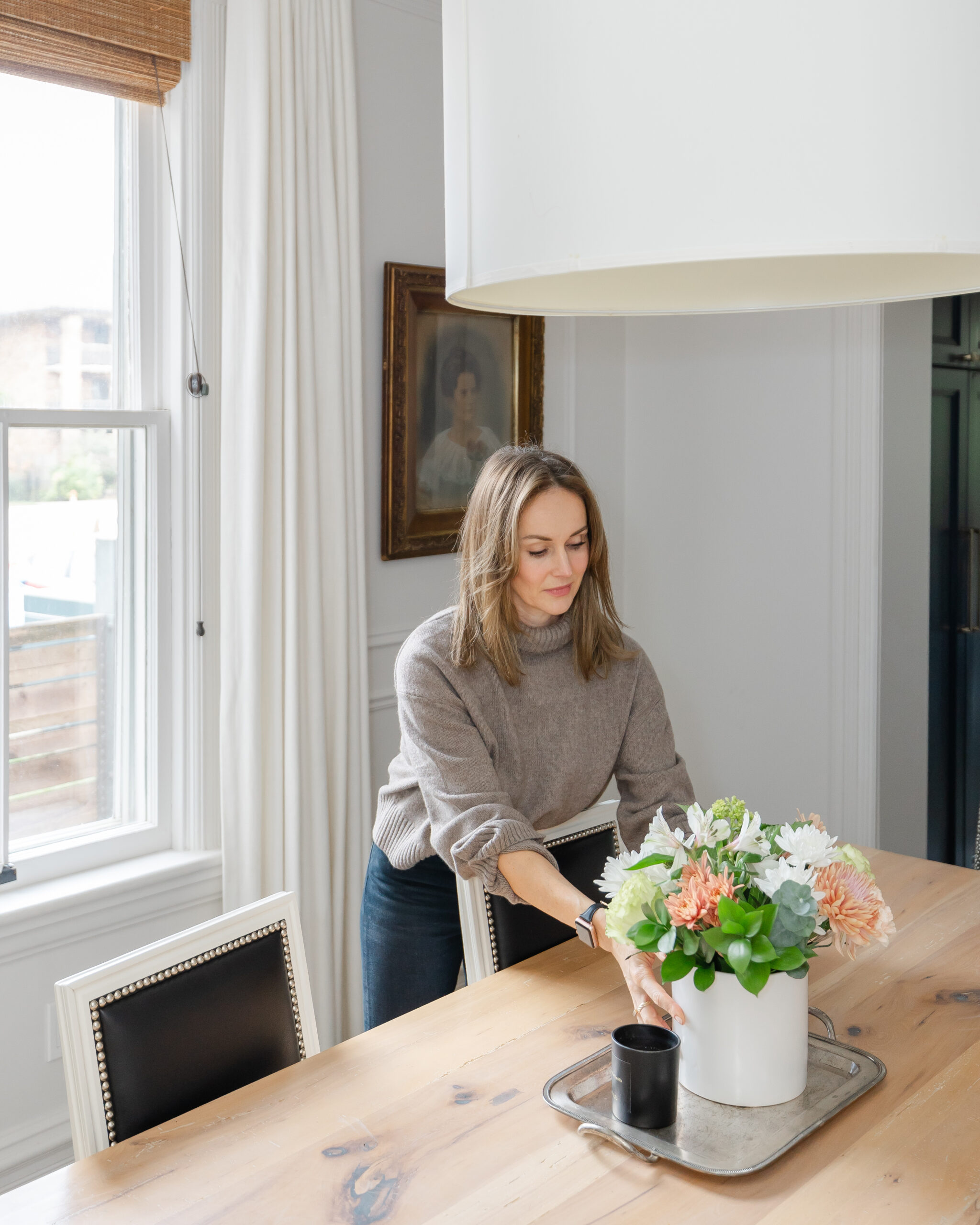 Interior Designer Staci Edwards placing flowers in a vase onto a dining table