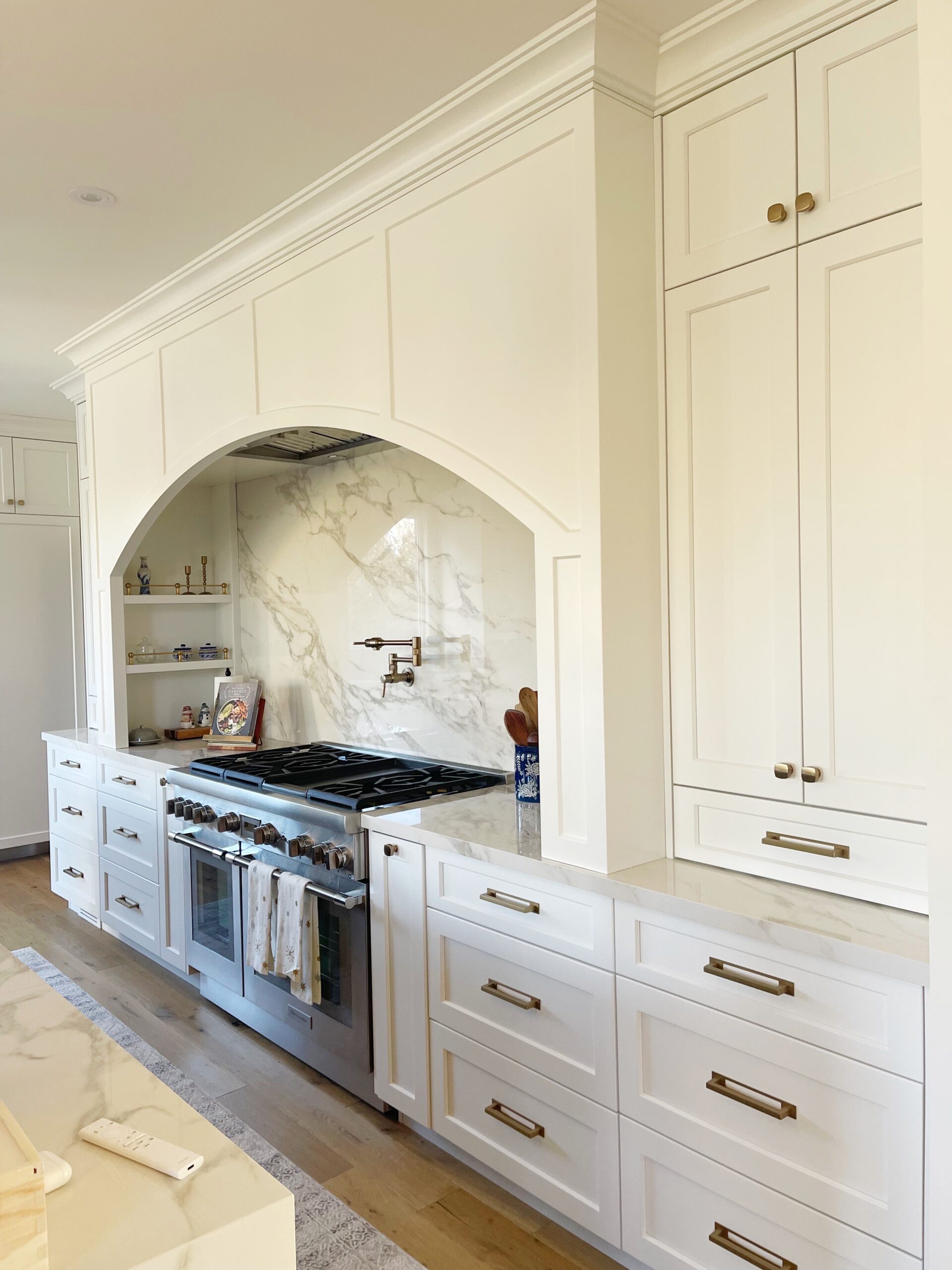 kitchen interior design showing white kitchen cabinetry and decorative range hood and gold hardware