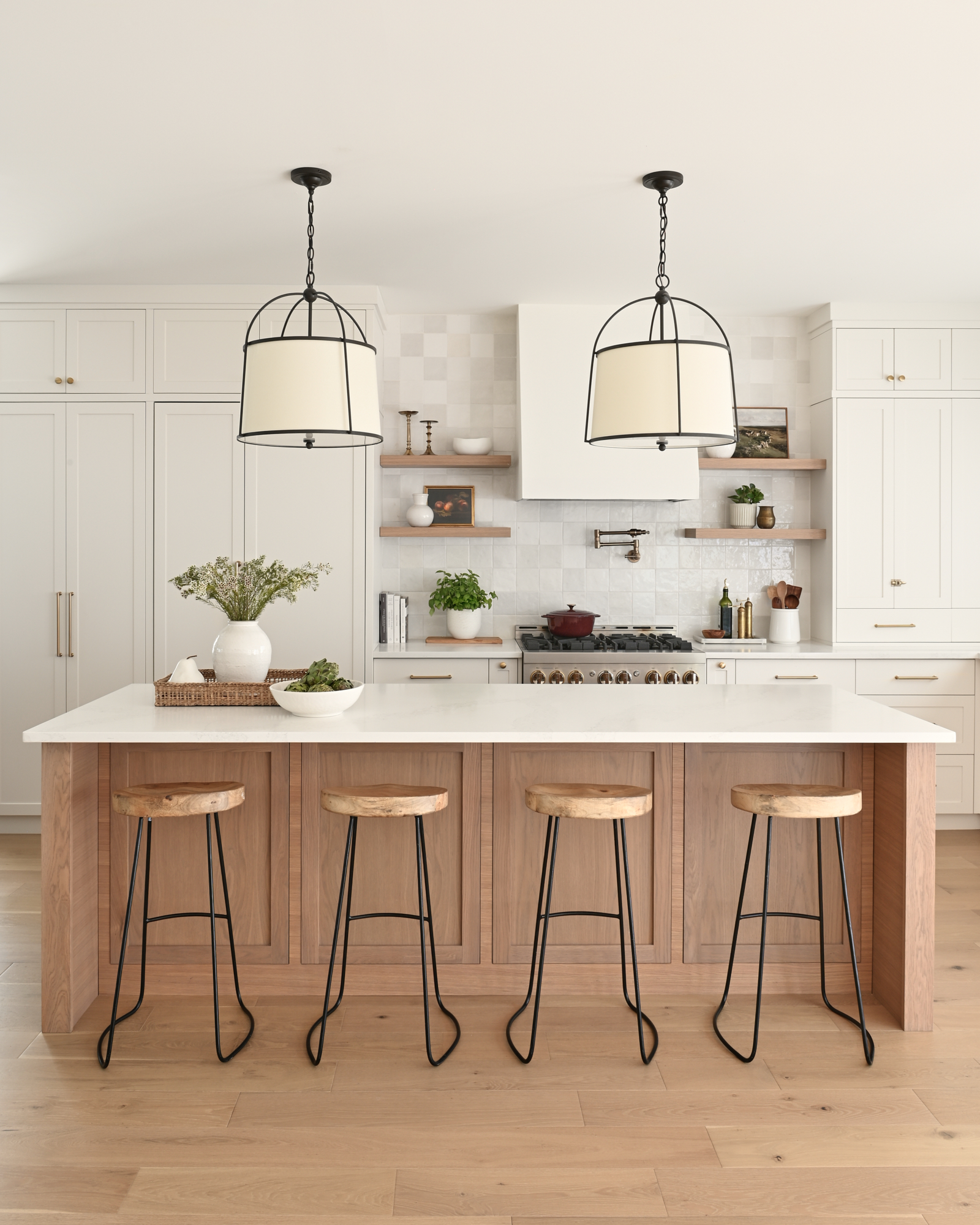 creamy white kitchen with zellige tile and gold hardware, wood island, and black accents