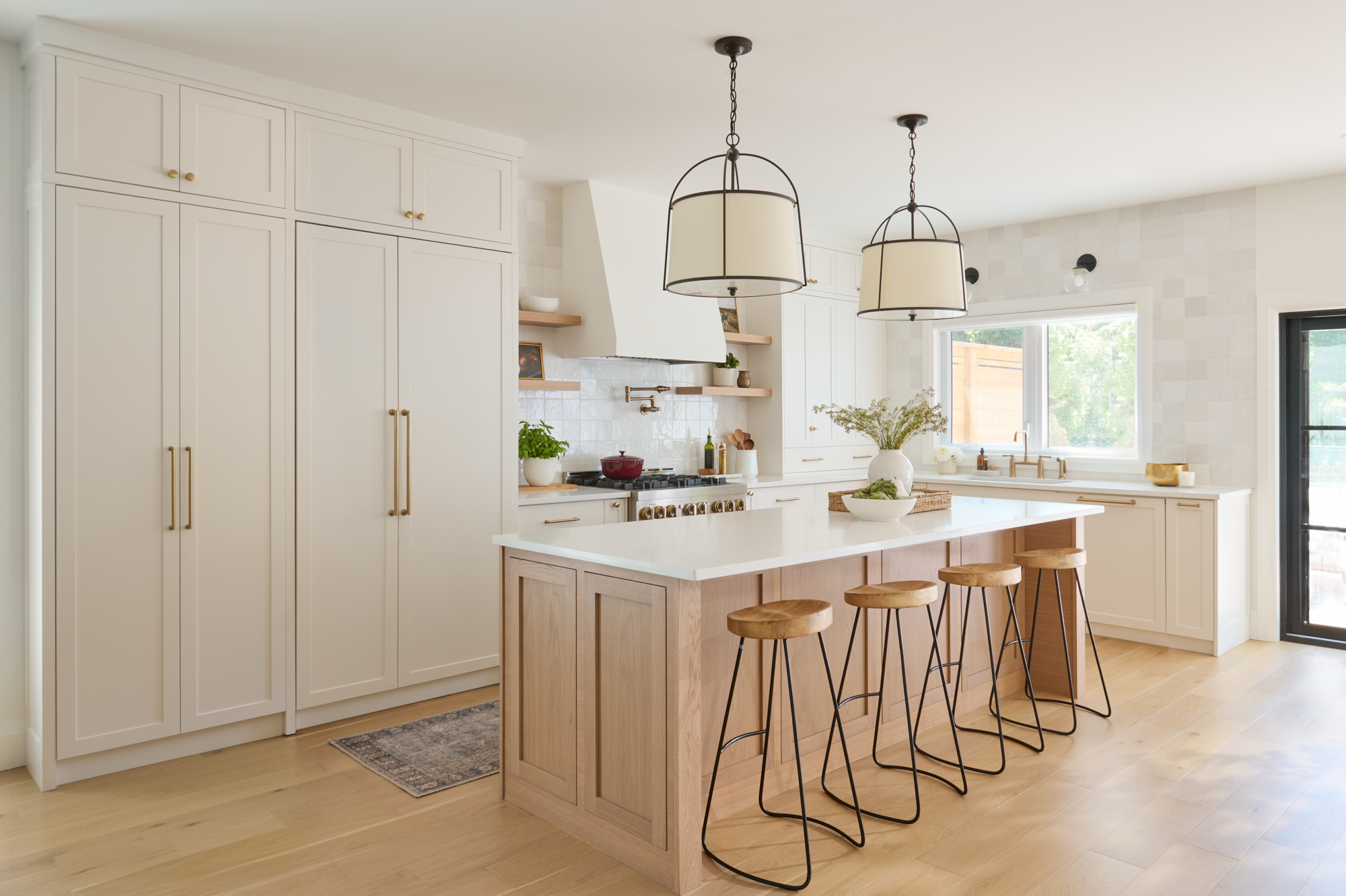 creamy white kitchen with zellige tile and gold hardware, wood island, and black accents