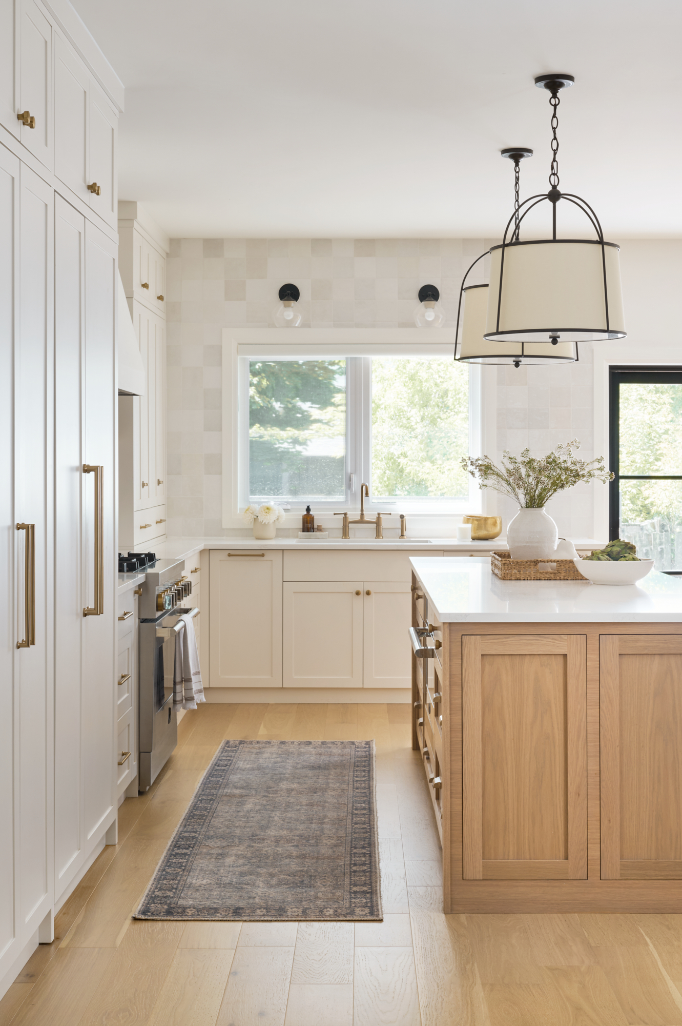 creamy white kitchen with zellige tile and gold hardware, wood island, and black accents