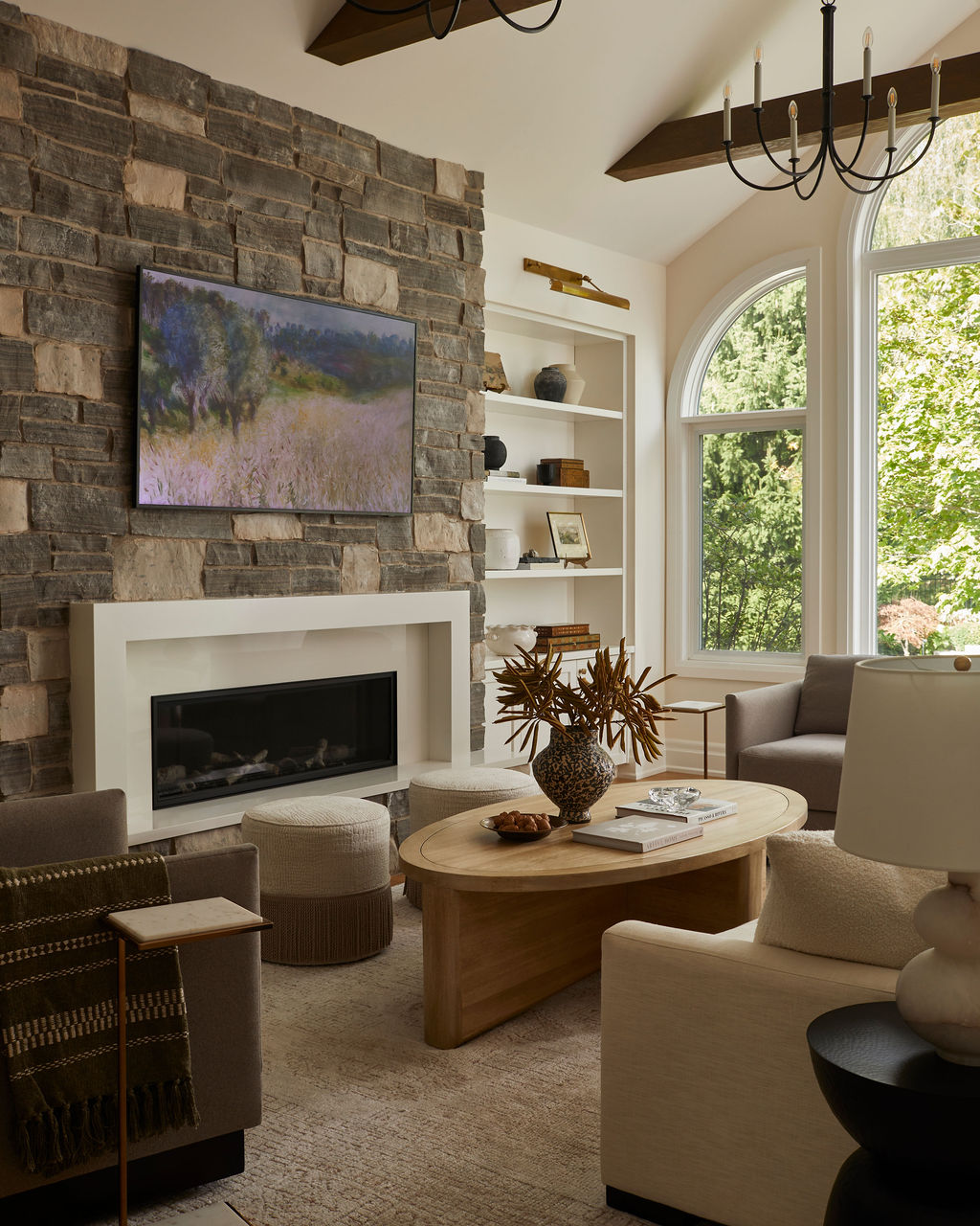 Bright living room with stone fireplace, exposed beams, and new window overlooking the backyard